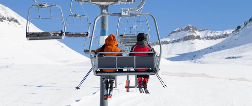 Two skiers on chair-lift and snow ski slope